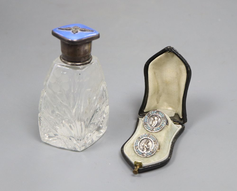 A cased pair of French white metal and enamel lapel buttons and a silver and enamel mounted glass scent bottle